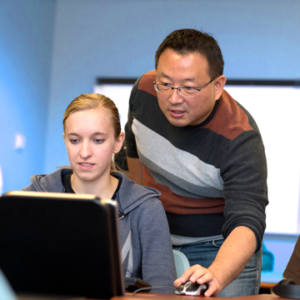 Photo of Dr. Yeh helping a student in the computer lab.