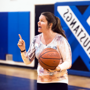 Photograph of Elizabeth Miner, Physical Education teacher, holding a basketball and talking.